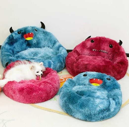 Small white dog in round cartoon-style dog bed with three other plush monster dog beds