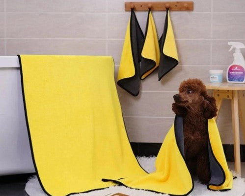 Brown dog sitting on the ground wrapped in an ultra-absorbent pet grooming towel