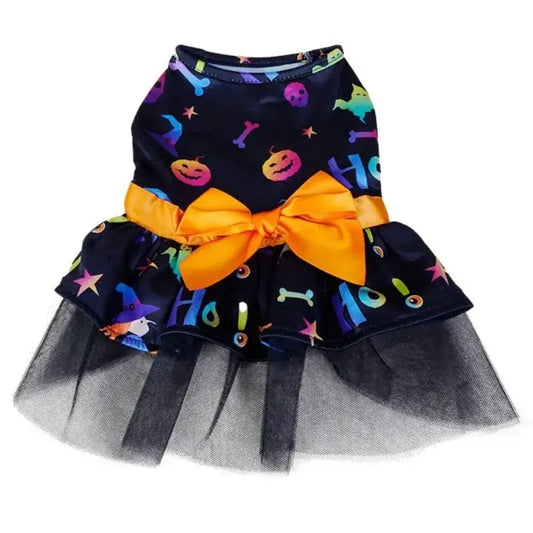 Small dog wearing a Halloween-themed dress with bow and puffy skirt.