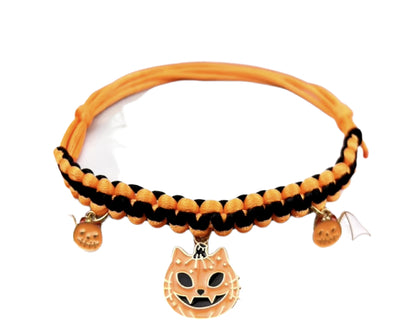 Cat wearing a Halloween breakaway collar with a small pumpkin pendant and festive woven design.