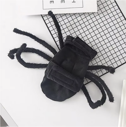 Dog dressed in a black Halloween spider costume with plush legs.