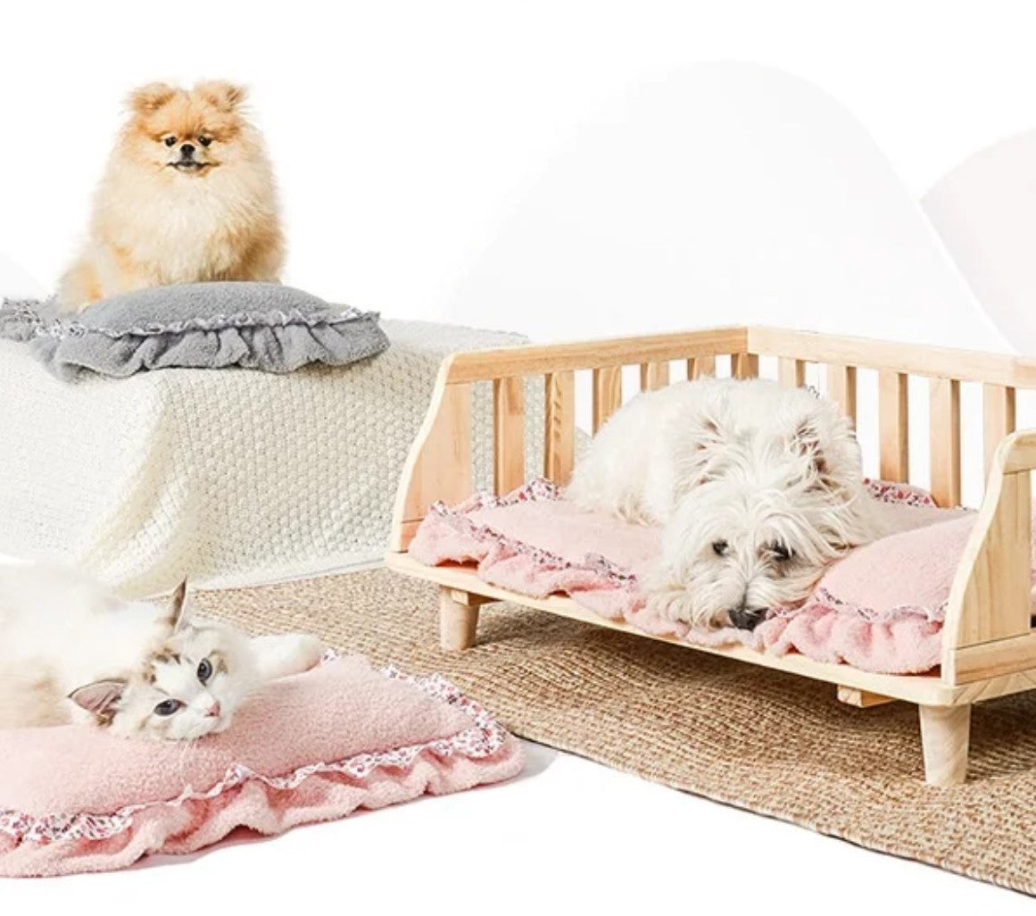 Small white dog lying on a pink pet mat with lace edge