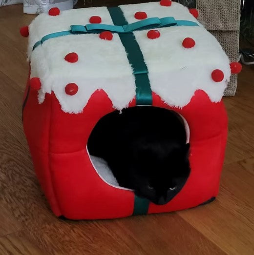 Black cat relaxing in red Christmas gift box-shaped cat bed with white top and red pom-pom accents - Customer review photo