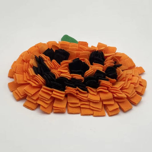 Dog sniffing a Halloween-themed pumpkin snuffle mat for hidden treats.