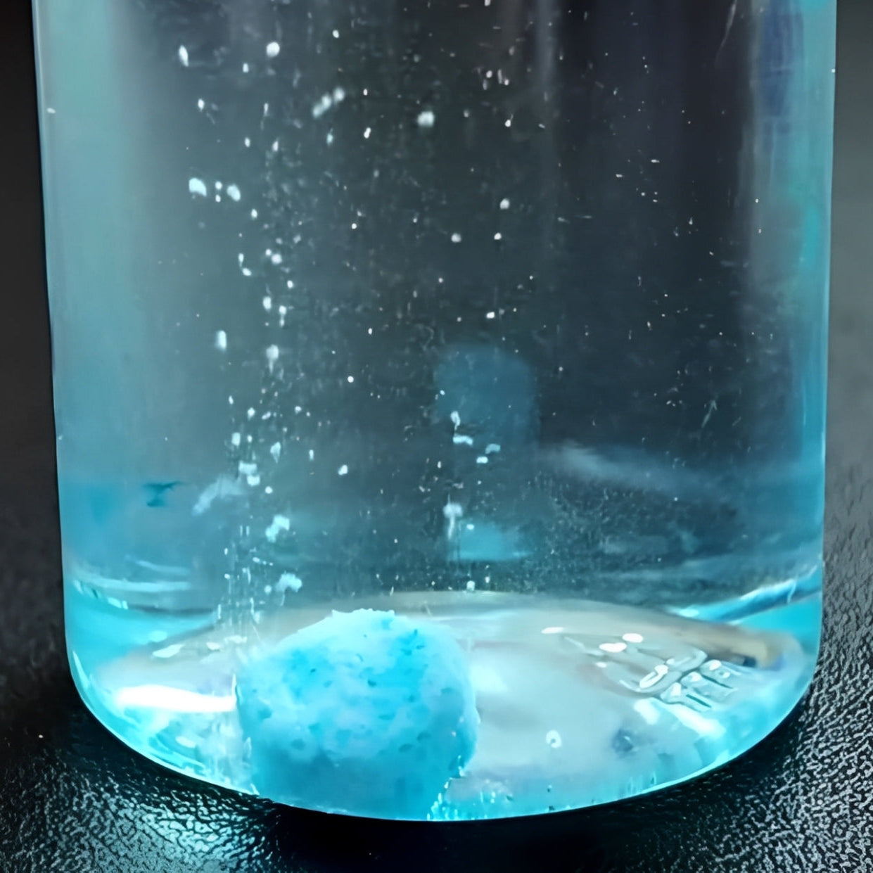 Close-up of a bottle with blue liquid and a bubble forming at the bottom, showcasing pet grooming products.