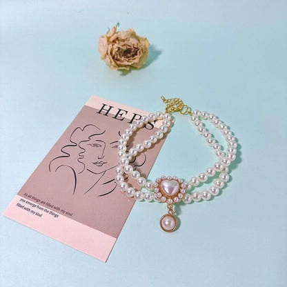 Small dog wearing gem pendant pearl necklace with lace accents