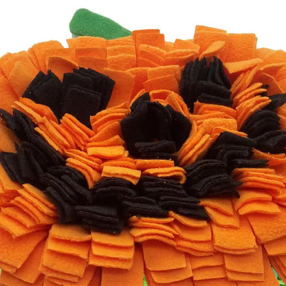 Dog sniffing a Halloween-themed pumpkin snuffle mat for hidden treats.