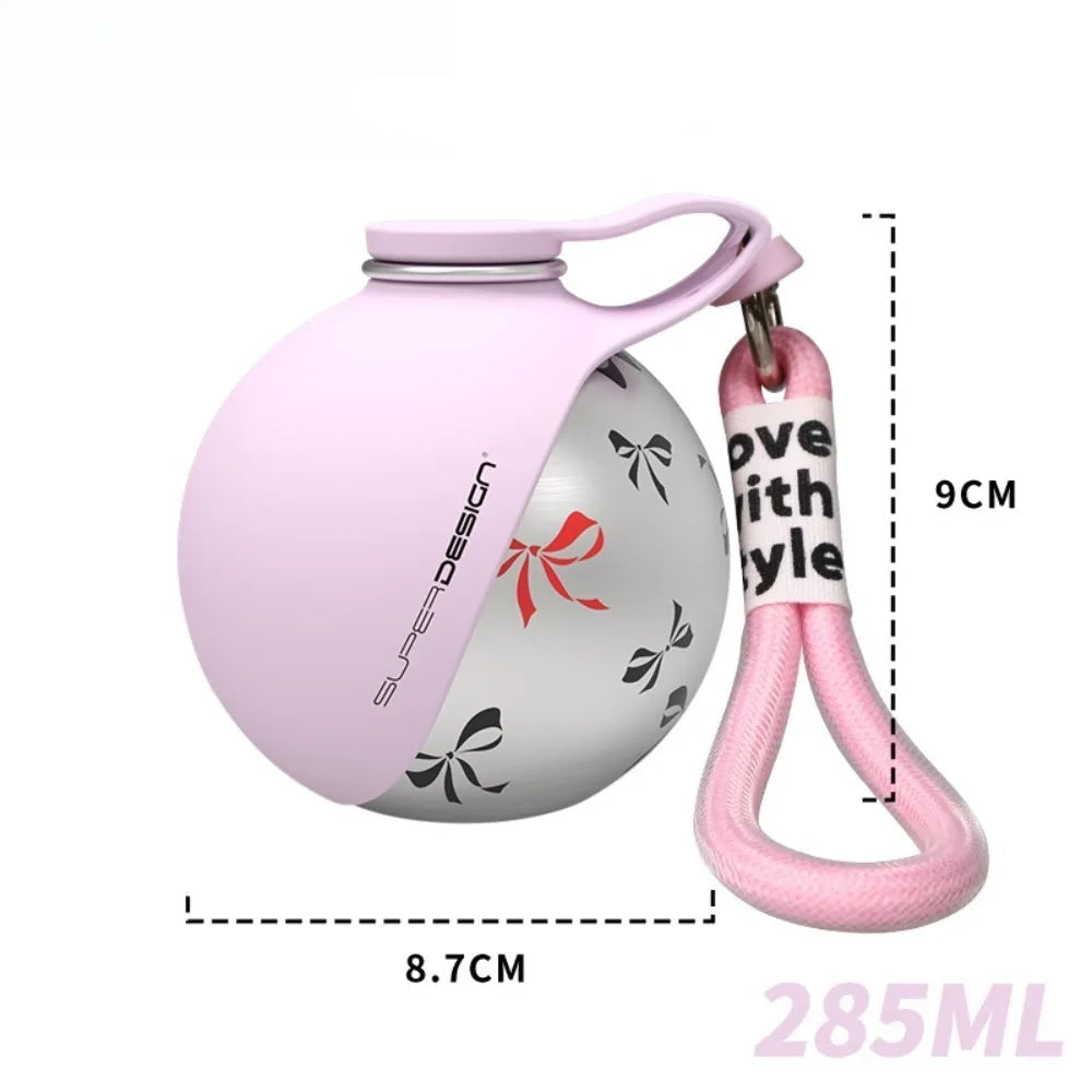 Dog Travel Water Bottle The Nomad™ Kinetic Hydration Orb in pink with a clip for easy carrying.