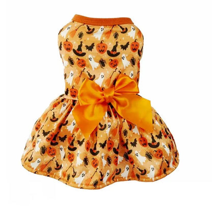 Small dog wearing a Halloween-themed dress with bow and puffy skirt.