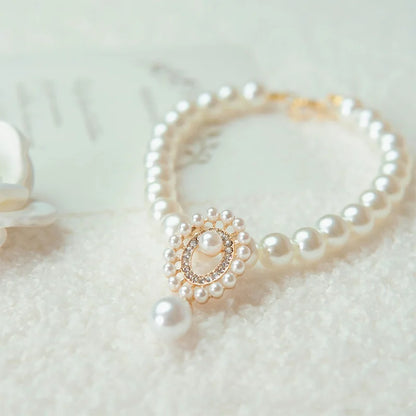 Small dog wearing gem pendant pearl necklace with lace accents