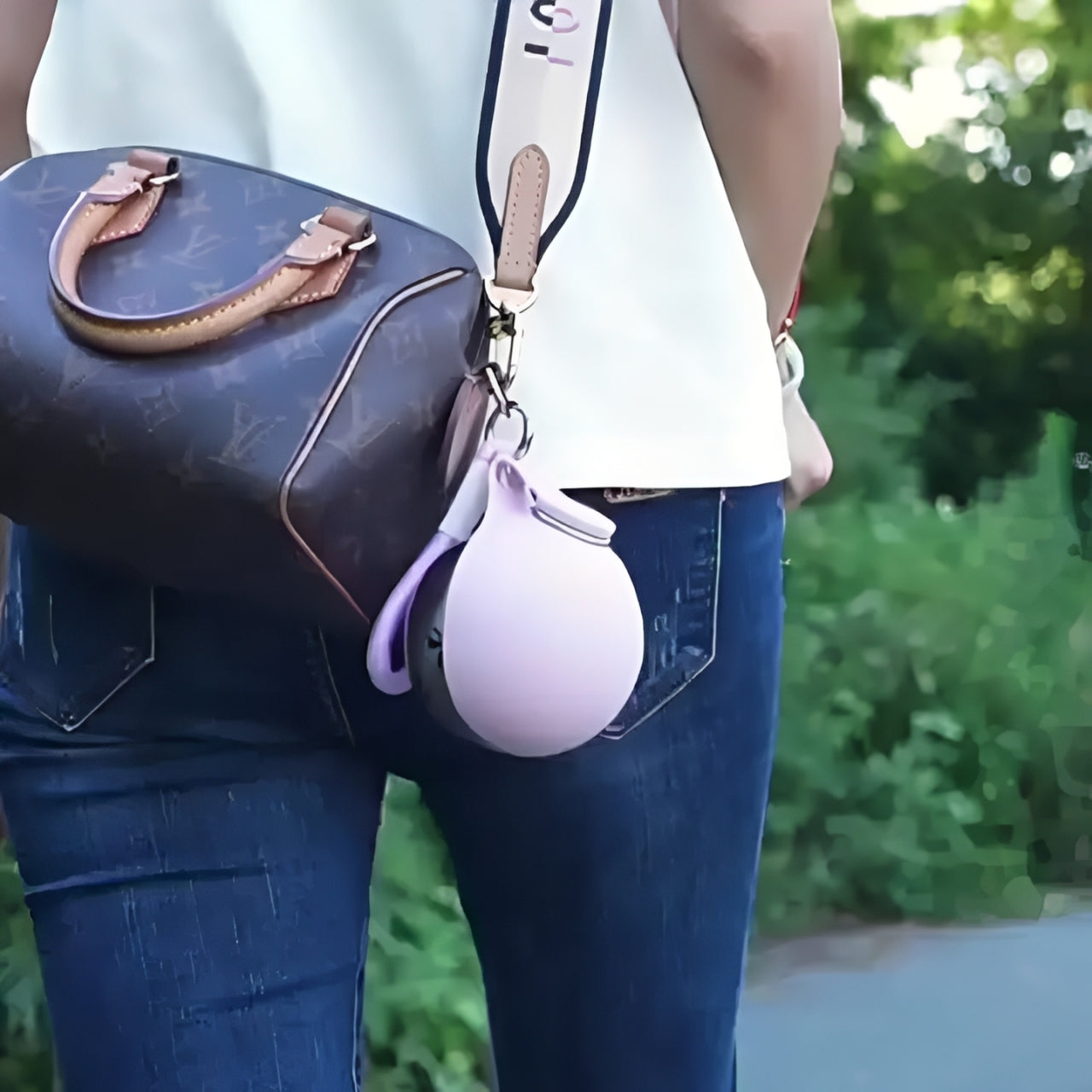 Dog travel water bottle attached to a stylish bag while walking outdoors.