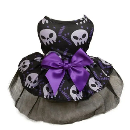 Small dog wearing a Halloween-themed dress with bow and puffy skirt.