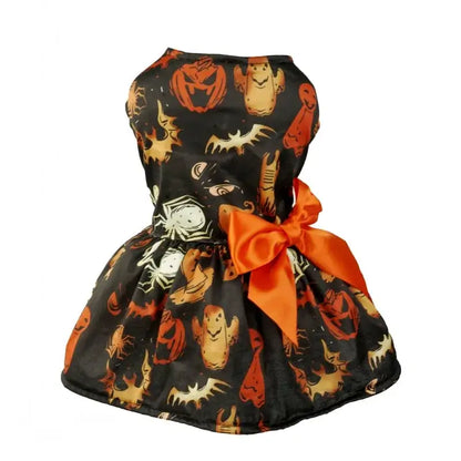 Small dog wearing a Halloween-themed dress with bow and puffy skirt.