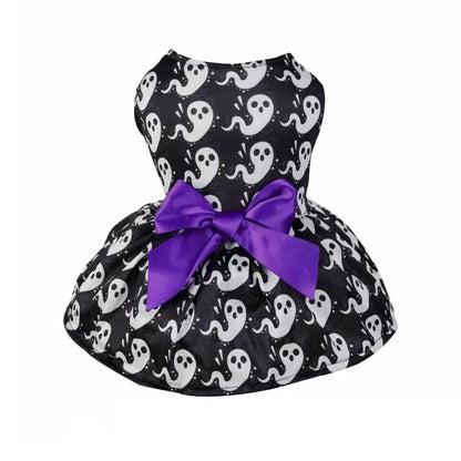 Small dog wearing a Halloween-themed dress with bow and puffy skirt.