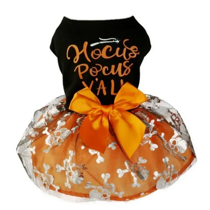 Small dog wearing a Halloween-themed dress with bow and puffy skirt.