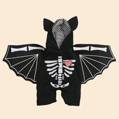 Dog wearing black bat wings costume, posing for Halloween in a spooky setting.