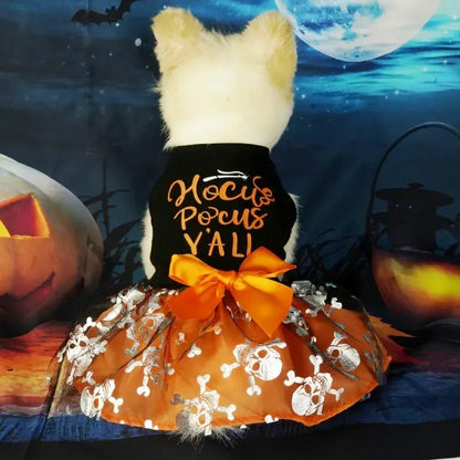 Small dog wearing a Halloween-themed dress with bow and puffy skirt.