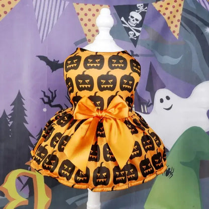 Small dog wearing a Halloween-themed dress with bow and puffy skirt.