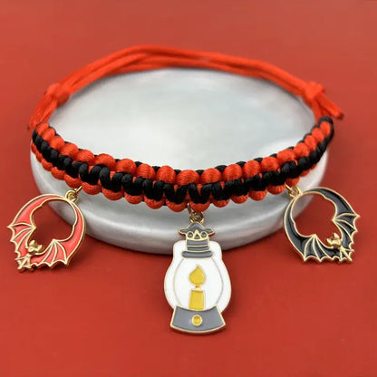 Cat wearing a Halloween breakaway collar with a small pumpkin pendant and festive woven design.