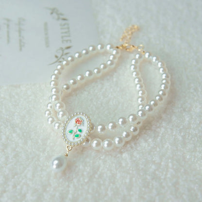 Small dog wearing gem pendant pearl necklace with lace accents