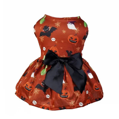 Small dog wearing a Halloween-themed dress with bow and puffy skirt.